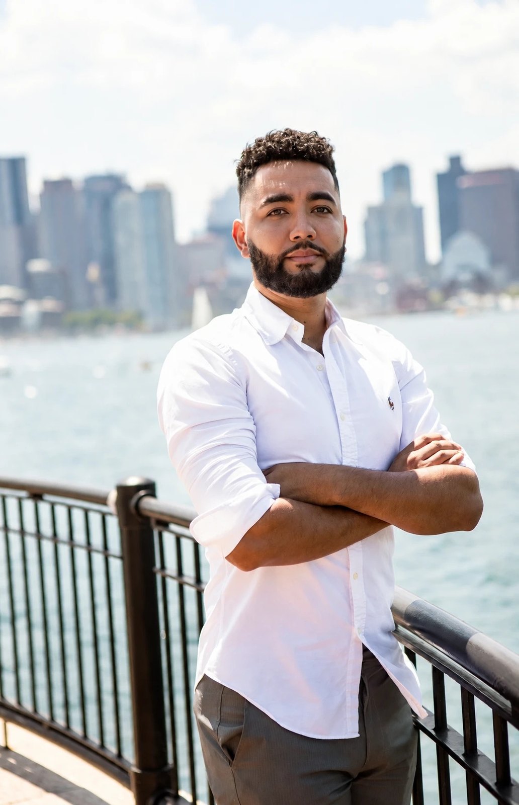 Mateus Magno, arms crossed, on the Boston waterfront