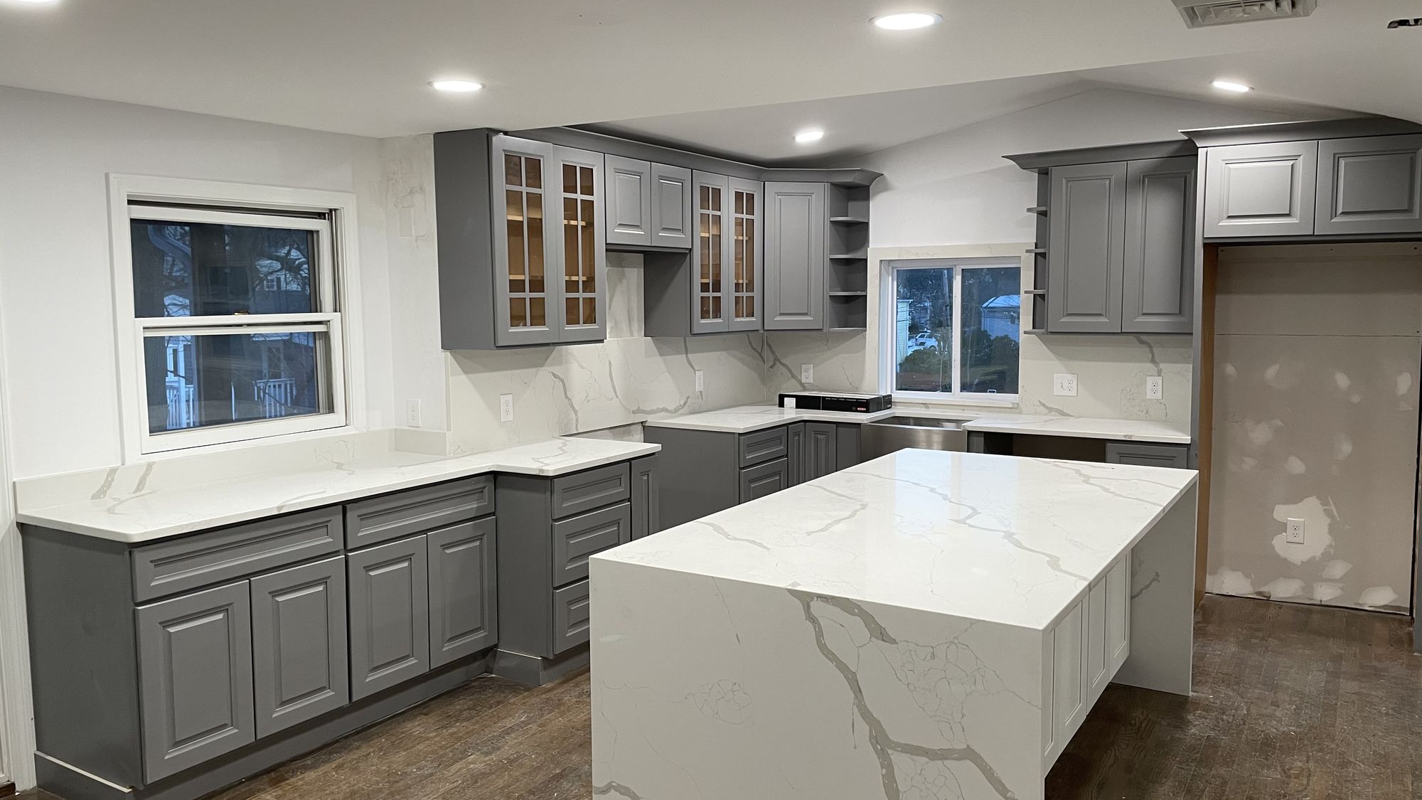 Gray shaker kitchen with quartz waterfall island