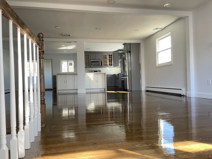 Renovated open living space with new hardwood floors and a white stair rail